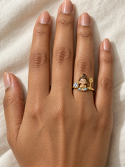 Bal Shiva Sadashiv ring – fair baby Shiva with crescent moon in namaste between a lab grown diamond solitaire and a gold trishul, worn on the ring finger
