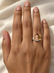 Bal Shiva Rudra ring – rosy-cheeked fair baby Shiva with crescent moon beside a lab grown diamond solitaire and a gold trishul, worn on the ring finger