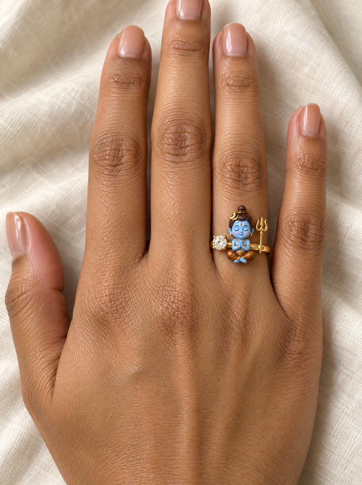 Bal Shiva Umapati ring – rosy-cheeked baby Shiva in namaste between a lab grown diamond and a gold trishul, worn on the ring finger