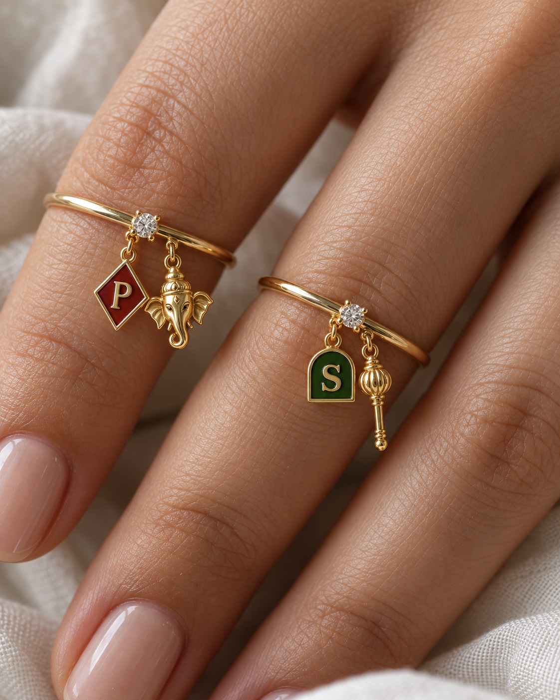 Ganesh Bajrang Lab Diamond Silver Couple Rings – pair of gold tone charm rings with maroon enamel diamond-shaped initial and gold Ganesha charm, and emerald-green enamel arch initial and gold gada charm (Hanuman), lab grown diamond solitaires, worn on the hand
