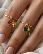 Ganesh Bajrang Lab Diamond Silver Couple Rings – pair of gold tone charm rings with maroon enamel diamond-shaped initial and gold Ganesha charm, and emerald-green enamel arch initial and gold gada charm (Hanuman), lab grown diamond solitaires, worn on the hand