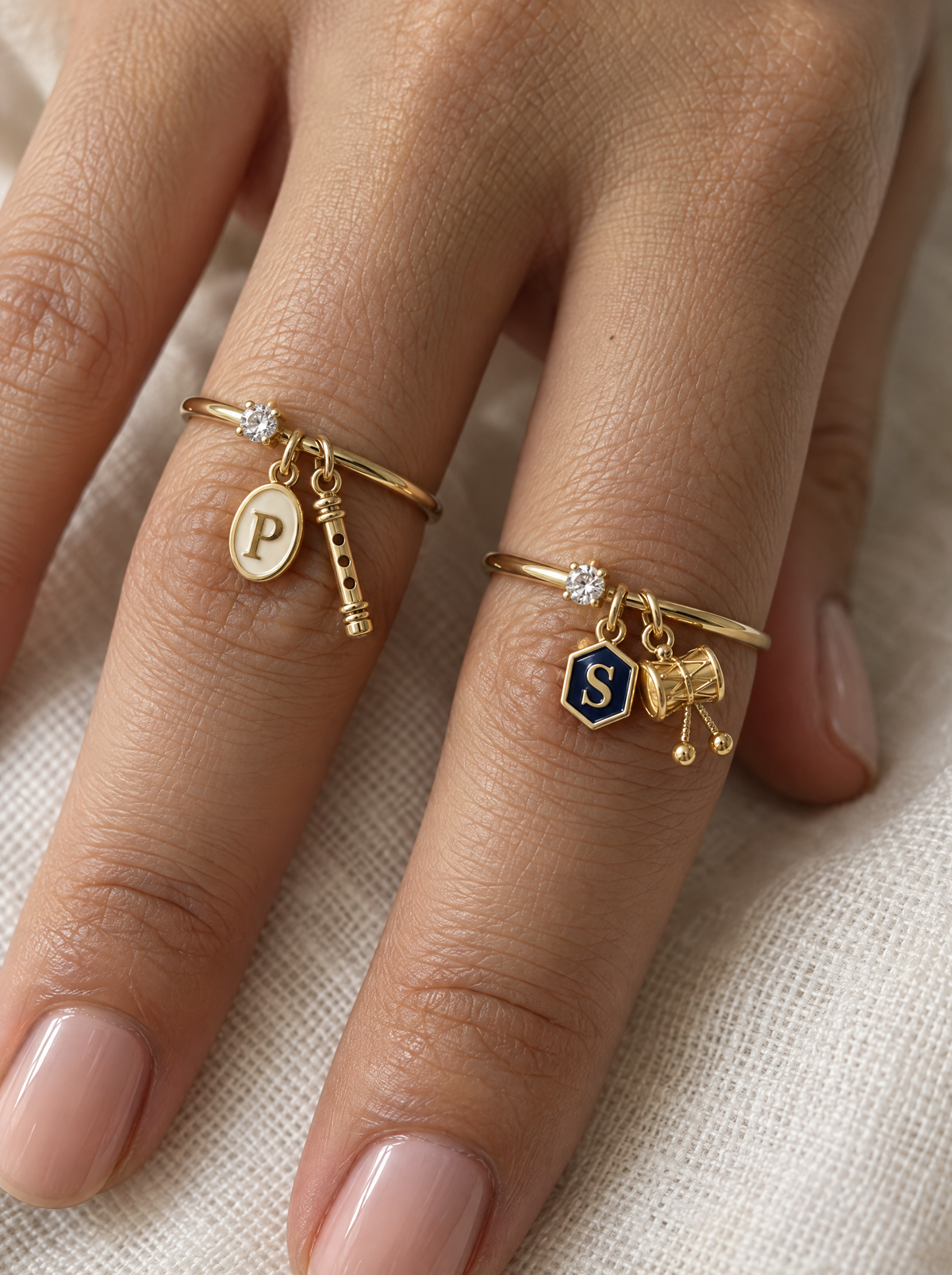 Kanha Bholenath Lab Diamond Silver Couple Rings – pair of gold tone charm rings with ivory enamel oval initial and gold bansuri charm (Krishna), and navy-blue enamel hexagon initial and gold damru charm (Shiva), lab grown diamond solitaires, worn on the hand