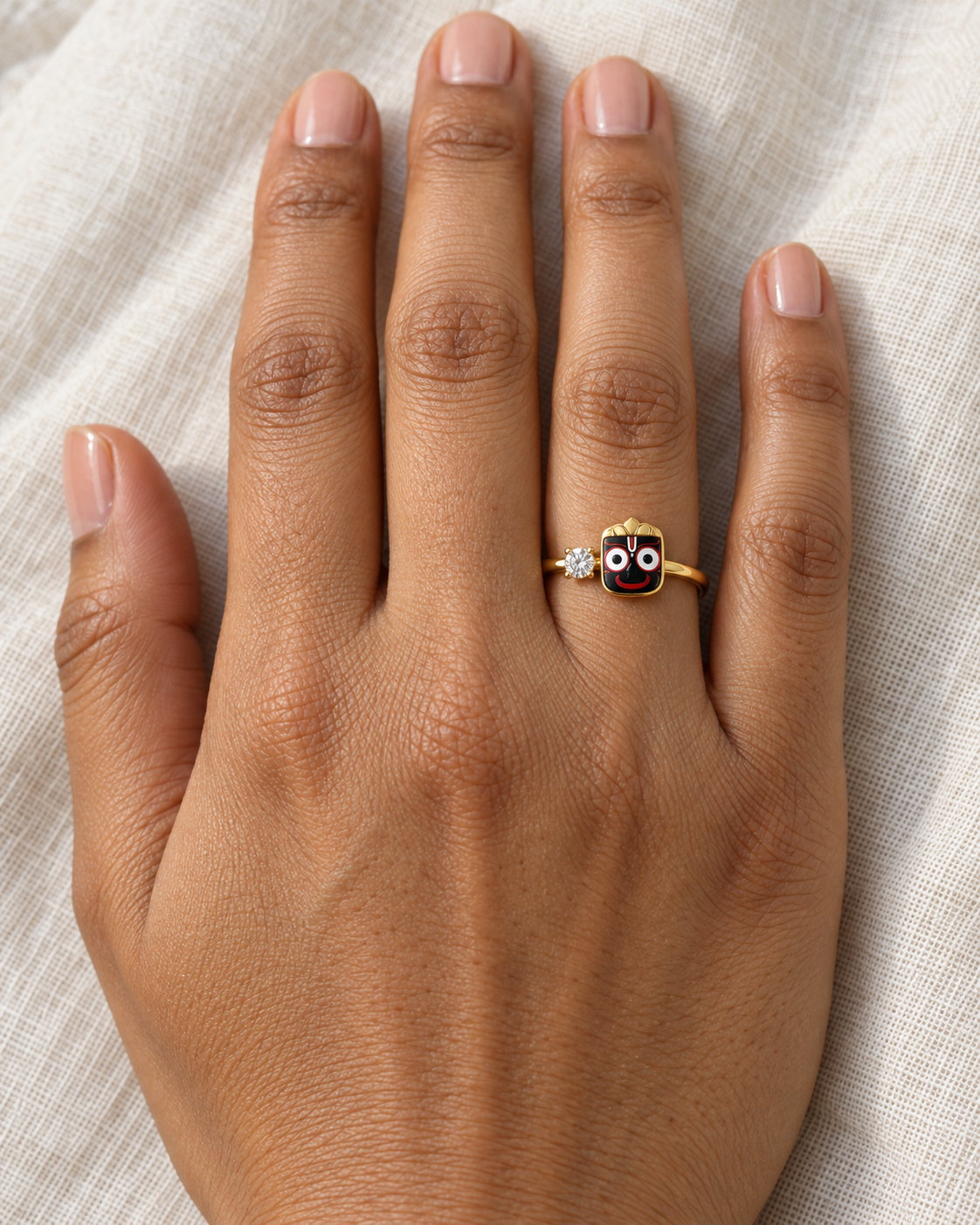 Jagannath Kalia ring – Lord Jagannath's face in black enamel with round eyes, red smile and gold crown beside a lab grown diamond solitaire, worn on the ring finger