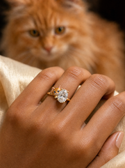 Peeping cat lab grown diamond ring in gold - ginger tabby with sapphire eyes beside an oval solitaire, worn on the hand - Fiona Diamonds