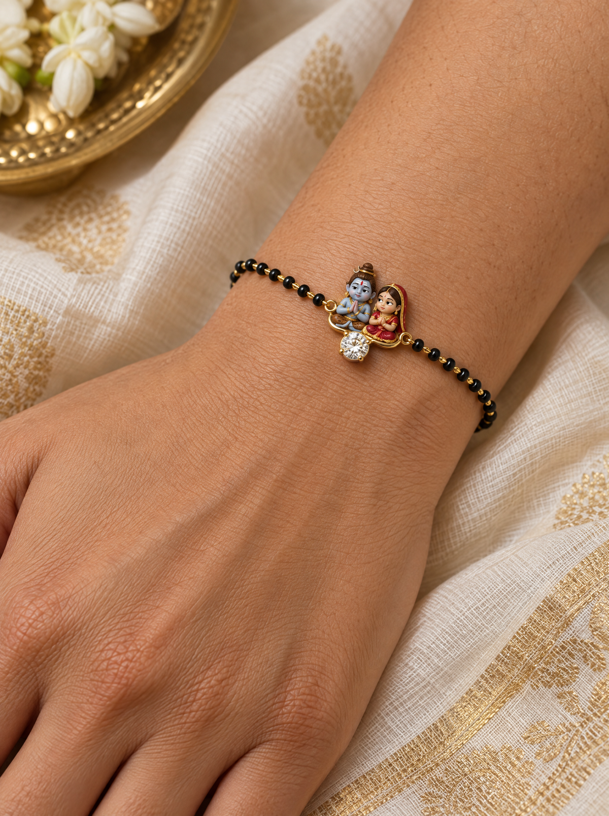 Pranam Shiv Gauri hand mangalsutra – enamel baby Shiva and Gauri in namaste in a gold frame with a lab grown diamond, black bead chain worn on the wrist